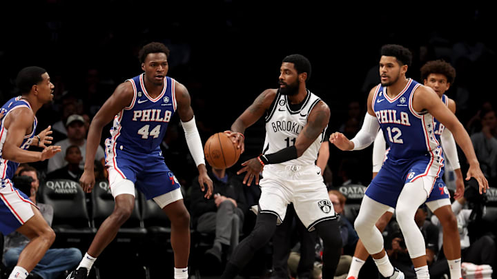 Oct 3, 2022; Brooklyn, New York, USA; Brooklyn Nets guard Kyrie Irving (11) passes the ball against Philadelphia 76ers forward Paul Reed (44) and forward Tobias Harris (12) during the first quarter at Barclays Center. Mandatory Credit: Brad Penner-Imagn Images