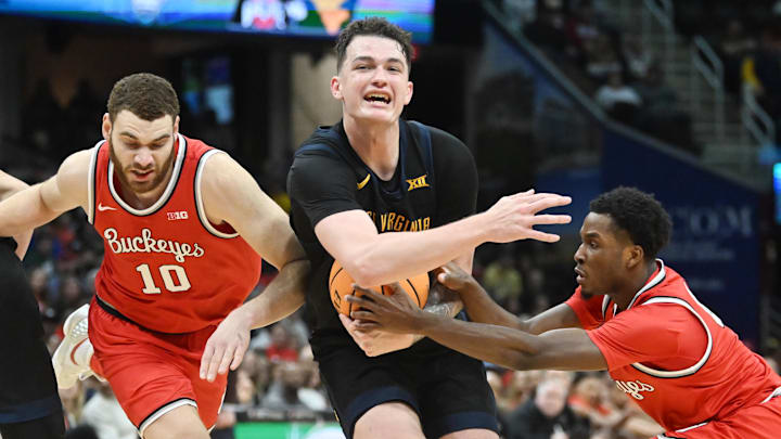 Dec 30, 2023; Cleveland, Ohio, USA; West Virginia Mountaineers forward Quinn Slazinski (11) drives to the basket against Ohio State Buckeyes guard Dale Bonner (4) and forward Jamison Battle (10) during the second half at Rocket Mortgage FieldHouse. Mandatory Credit: Ken Blaze-Imagn Images