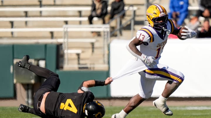 Dec 6, 2024; Birmingham, AL, USA; Cherokee County's Tristan Brown (4) tries to hang on for a tackle as Jackson's Ezavier Crowell (13) pulls away at Protective Stadium in the AHSAA 4A State Championship game.