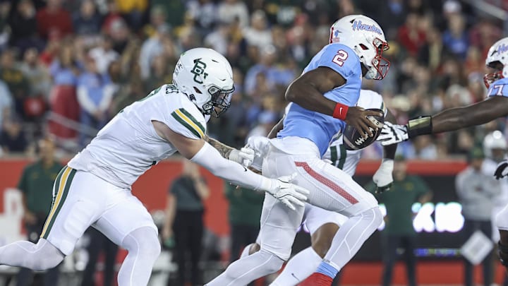 Nov 23, 2024; Houston, Texas, USA; Houston Cougars quarterback Zeon Chriss (2) runs with the ball as Baylor Bears linebacker Matt Jones (2) attempts to make a tackle during the second quarter at TDECU Stadium. Mandatory Credit: Troy Taormina-Imagn Images
