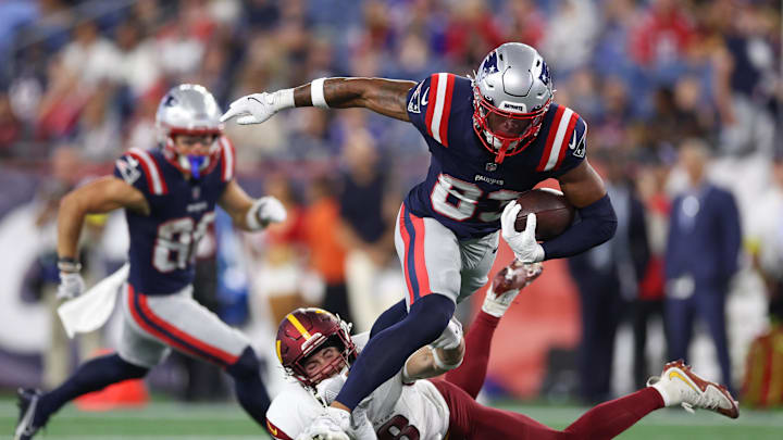 Aug 8, 2025; Foxborough, Massachusetts, USA; New England Patriots receiver John Jiles (83) breaks a tackle by Washington Commanders saftey Ben Nikkel (48) during the second half at Gillette Stadium. Mandatory Credit: Paul Rutherford-Imagn Images
