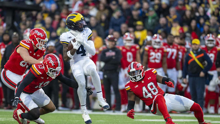 Nov 22, 2025; College Park, Maryland, USA;  Michigan Wolverines wide receiver Andrew Marsh (4) spins on a punt return in-between Maryland Terrapins defenders during the first half  at SECU Stadium. Mandatory Credit: Tommy Gilligan-Imagn Images