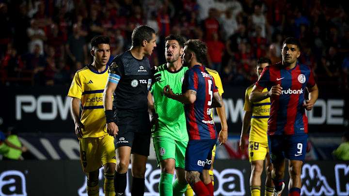 Guillermo Fernandez of Boca Juniors (L), referee Pablo...