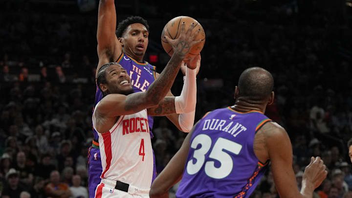 Mar 30, 2025; Phoenix, Arizona, USA; Houston Rockets guard Jalen Green (4) drives between Phoenix Suns forward Kevin Durant (35) and center Oso Ighodaro in the first half at Footprint Center. Mandatory Credit: Rick Scuteri-Imagn Images