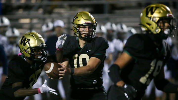 Iowa City West’s quarterback Jack Wallace (10) hands the ball off to Butali Butali (35) while playing Pleasant Valley Friday, Oct. 18, 2024 in Iowa City, Iowa.