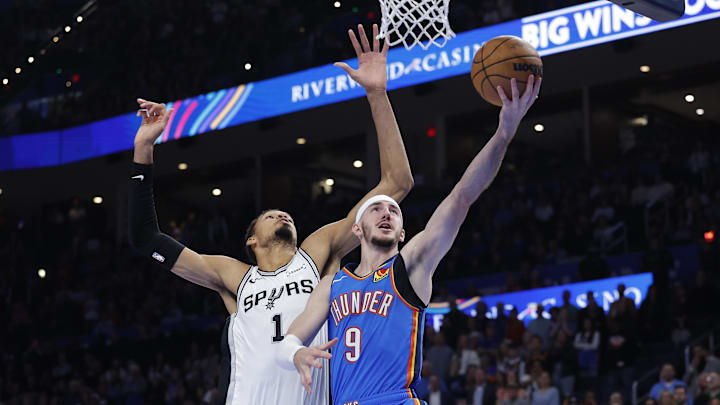 Jan 13, 2026; Oklahoma City, Oklahoma, USA; Oklahoma City Thunder guard Alex Caruso (9) goes to the basket past San Antonio Spurs forward/center Victor Wembanyama (1) during the second half at Paycom Center. Mandatory Credit: Alonzo Adams-Imagn Images