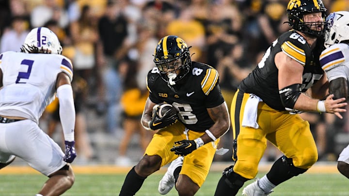 Aug 30, 2025; Iowa City, Iowa, USA; Iowa Hawkeyes running back Terrell Washington Jr. (8) runs the ball as offensive lineman Logan Jones (65) blocks and Albany Great Danes defensive back Denzel Patrick (2) looks to make the tackle during the third quarter at Kinnick Stadium. Mandatory Credit: Jeffrey Becker-Imagn Images