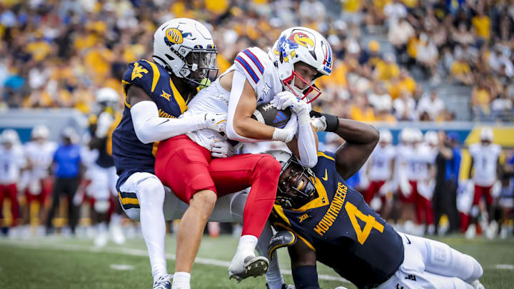 Sep 21, 2024; Morgantown, West Virginia, USA; Kansas Jayhawks wide receiver Luke Grimm (11) makes a catch and is tackled by West Virginia Mountaineers linebacker Trey Lathan (4) and West Virginia Mountaineers cornerback Ayden Garnes (0) during the second quarter at Mountaineer Field at Milan Puskar Stadium. Mandatory Credit: Ben Queen-Imagn Images
