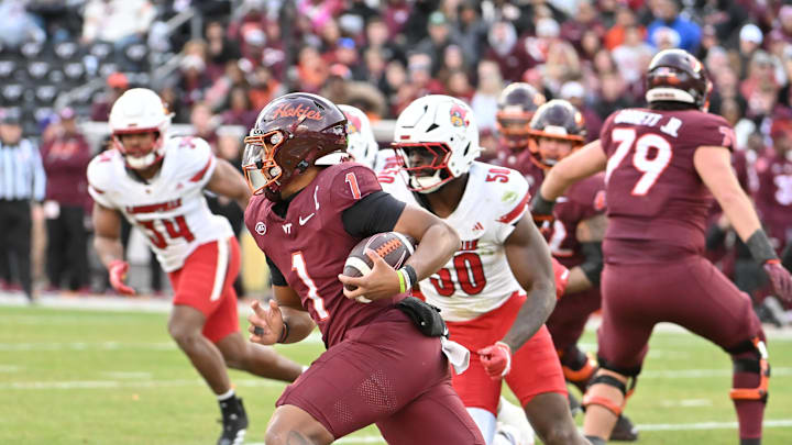 Nov 1, 2025; Blacksburg, Virginia, USA; Virginia Tech Hokies quarterback Kyron Drones (1) runs the ball as Louisville Cardinals defensive lineman Clev Lubin (50) defends during the third quarter at Lane Stadium. Mandatory Credit: Brian Bishop-Imagn Images