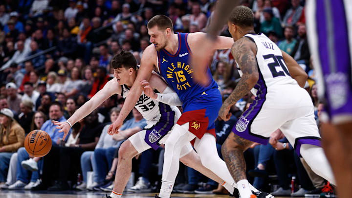 Mar 5, 2025; Denver, Colorado, USA; Sacramento Kings forward Jake LaRavia (33) strips the ball away from Denver Nuggets center Nikola Jokic (15) as guard Markelle Fultz (20) defends in the first quarter at Ball Arena. Mandatory Credit: Isaiah J. Downing-Imagn Images