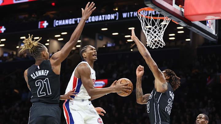 Nov 7, 2025; Brooklyn, New York, USA;  Detroit Pistons guard Ausar Thompson (9) drives in between Brooklyn Nets forward Noah Clowney (21) and center Nic Claxton (33) in the second quarter at Barclays Center. Mandatory Credit: Wendell Cruz-Imagn Images