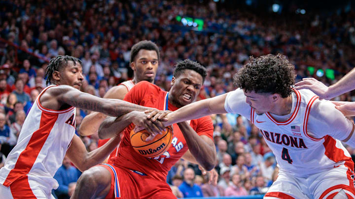 Mar 8, 2025; Lawrence, Kansas, USA; Kansas Jayhawks forward Flory Bidunga (40) protects the ball from Arizona Wildcats guard Liam Lloyd (11) and Arizona Wildcats forward Trey Townsend (4) during the second half at Allen Fieldhouse. Mandatory Credit: William Purnell-Imagn Images