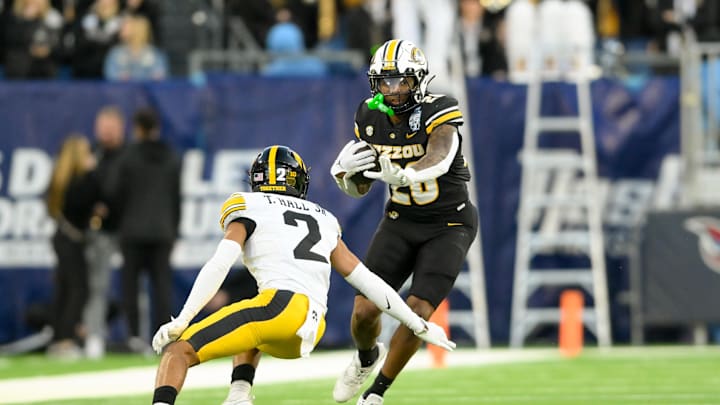 Dec 30, 2024; Nashville, TN, USA;  Missouri Tigers running back Jamal Roberts (20) avoids the tackle of Iowa Hawkeyes defensive back TJ Hall (2) during the second half at Nissan Stadium. Mandatory Credit: Steve Roberts-Imagn Images