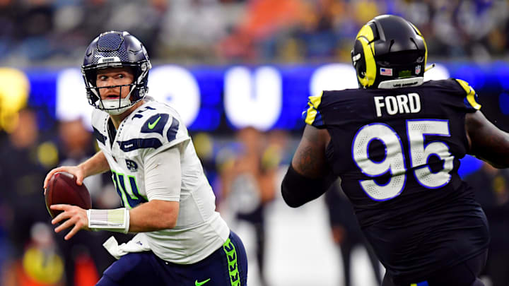 Nov 16, 2025; Inglewood, California, USA; Seattle Seahawks quarterback Sam Darnold (14) rolls out to pass against Los Angeles Rams defensive tackle Poona Ford (95) during the second half at SoFi Stadium. Mandatory Credit: Gary A. Vasquez-Imagn Images