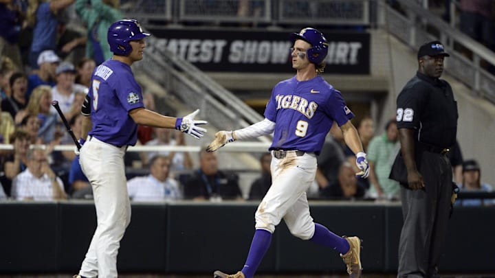 Jun 27, 2017; Omaha, NE, USA; LSU Tigers center fielder Zach Watson (9) celebrates with infielder Jake Slaughter (5) after scoring during the seventh inning against the Florida Gators in game two of the championship series of the 2017 College World Series at TD Ameritrade Park Omaha. 