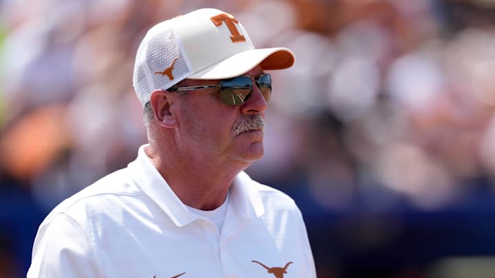 Texas coach Mike White walks to the first base coaches box during a Women's College World Series softball game between the University of Oklahoma Sooners (OU) and the Texas Longhorns.