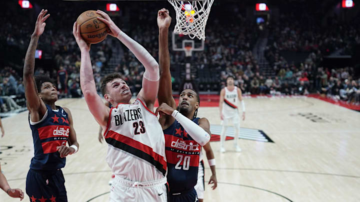 Mar 17, 2025; Portland, Oregon, USA; Portland Trail Blazers center Donovan Clingan (23) shoots pressured by Washington Wizards power forward Alex Sarr (20) during the first half at Moda Center. Mandatory Credit: Soobum Im-Imagn Images