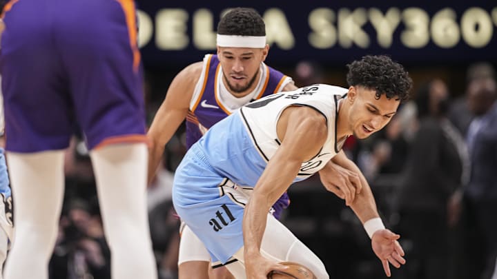 Jan 14, 2025; Atlanta, Georgia, USA; Atlanta Hawks forward Zaccharie Risacher (10) tries to keep the ball away from Phoenix Suns guard Devin Booker (1) during the first half at State Farm Arena. Mandatory Credit: Dale Zanine-Imagn Images