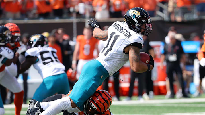 Sep 14, 2025; Cincinnati, Ohio, USA;  Jacksonville Jaguars wide receiver Parker Washington (11) runs the ball as Cincinnati Bengals cornerback Dax Hill (23) makes the tackle during the first quarter at Paycor Stadium. Mandatory Credit: Joseph Maiorana-Imagn Images
