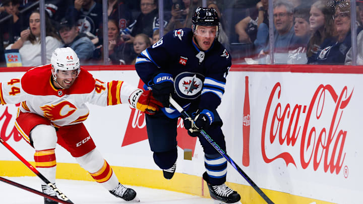 Sep 27, 2025; Winnipeg, Manitoba, CAN;  Winnipeg Jets forward Jonathan Toews (19) tries to skates away from Calgary Flames defenseman Joel Hamley (44) during the second period at Canada Life Centre. Mandatory Credit: Terrence Lee-Imagn Images