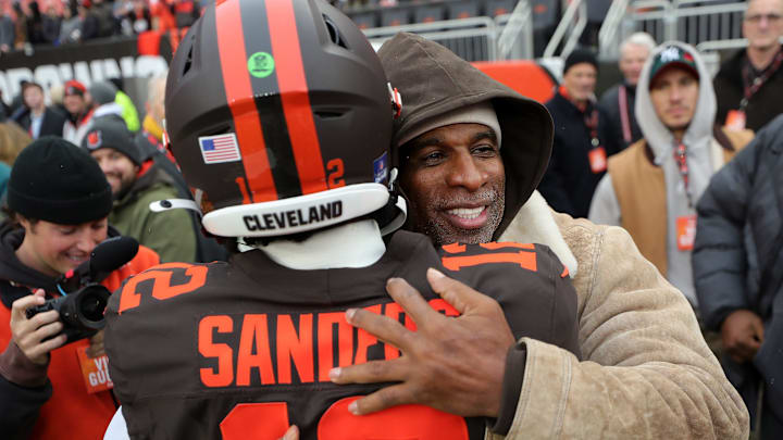 NFL legend Deion Sanders Sr., facing, hugs his son Shedeur Sanders before an NFL football game at Huntington Bank Field, Dec. 7, 2025, in Cleveland, Ohio.