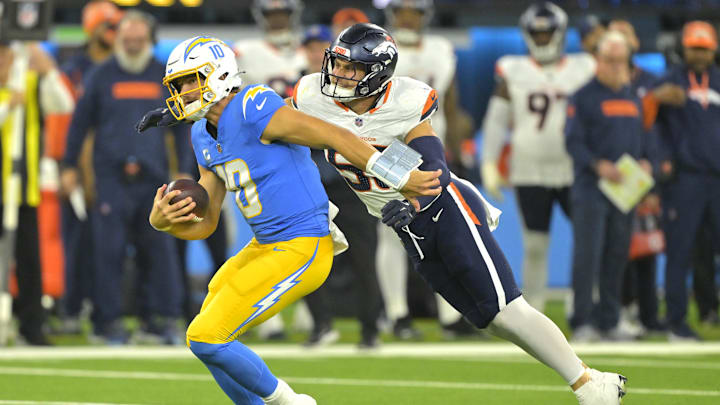 Dec 19, 2024; Inglewood, California, USA;  Los Angeles Chargers quarterback Justin Herbert (10) is brought down by Denver Broncos linebacker Cody Barton (55) after an 18-yard run in the second half at SoFi Stadium. Mandatory Credit: Jayne Kamin-Oncea-Imagn Images