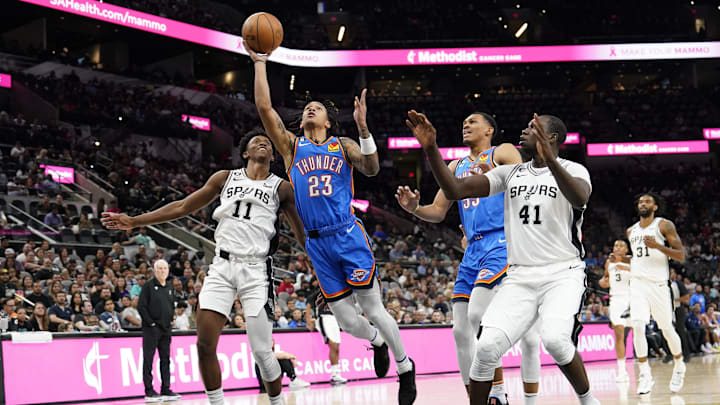 Oklahoma City Thunder guard Tre Mann (23) drives to the basket between San Antonio Spurs guard Josh Primo (11) and center Gorgui Dieng (41) during the second half at AT&T Center. Mandatory Credit: Scott Wachter-Imagn Images