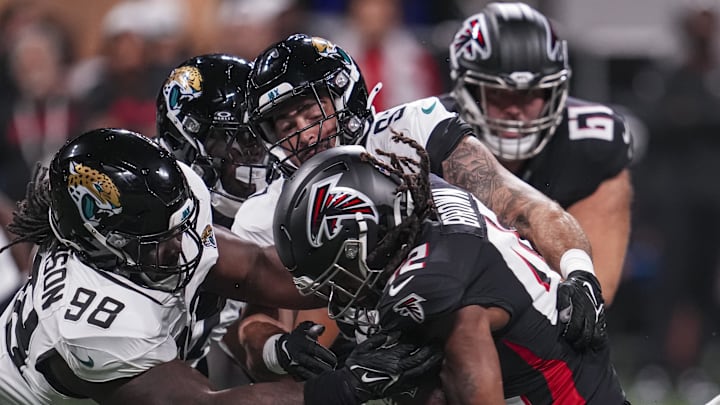 Aug 23, 2024; Atlanta, Georgia, USA; Atlanta Falcons running back Spencer Brown (42) is tackled by Jacksonville Jaguars defensive tackle Jordan Jefferson (98) and defensive end Joe Gaziano (97) during the second half at Mercedes-Benz Stadium. 