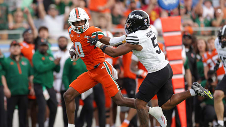 Dec 28, 2024; Orlando, FL, USA; Miami Hurricanes wide receiver Joshisa Trader (0) holds off Iowa State Cyclones defensive back Myles Purchase (5) in the second quarter during the Pop Tarts bowl at Camping World Stadium. Mandatory Credit: Nathan Ray Seebeck-Imagn Images
