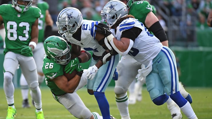 Dec 29, 2024; Philadelphia, Pennsylvania, USA; Philadelphia Eagles running back Saquon Barkley (26) is tackled by Dallas Cowboys cornerback Jourdan Lewis (2) and linebacker Eric Kendricks (50) during the second quarter at Lincoln Financial Field. Mandatory Credit: Eric Hartline-Imagn Images
