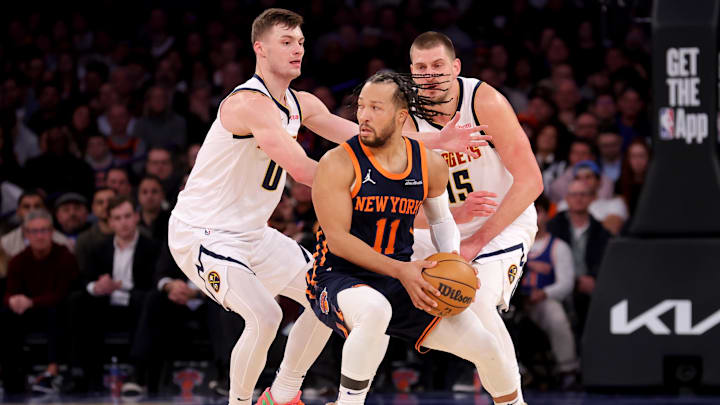 Jan 29, 2025; New York, New York, USA; New York Knicks guard Jalen Brunson (11) controls the ball against Denver Nuggets guard Christian Braun (0) and center Nikola Jokic (15) during the fourth quarter at Madison Square Garden. Mandatory Credit: Brad Penner-Imagn Images