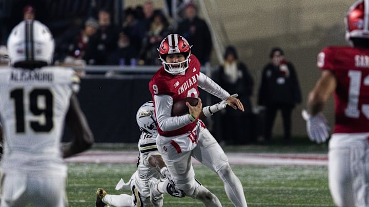 Nov 30, 2024; Bloomington, Indiana, USA; Indiana Hoosiers quarterback Kurtis Rourke (9) runs the ball while Purdue Boilermakers defensive back Kyndrich Breedlove (10)  defends in the second half at Memorial Stadium. Mandatory Credit: Trevor Ruszkowski-Imagn Images