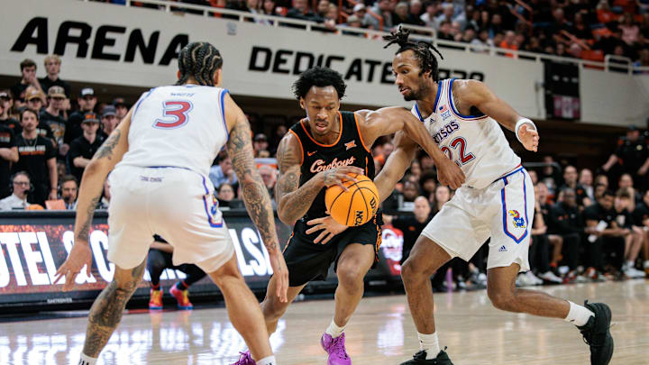 Feb 18, 2026; Stillwater, Oklahoma, USA; Oklahoma State Cowboys guard Anthony Roy (9) drives to the basket around Kansas Jayhawks guard Darryn Peterson (22) during the first half at Gallagher-Iba Arena. Mandatory Credit: William Purnell-Imagn Images