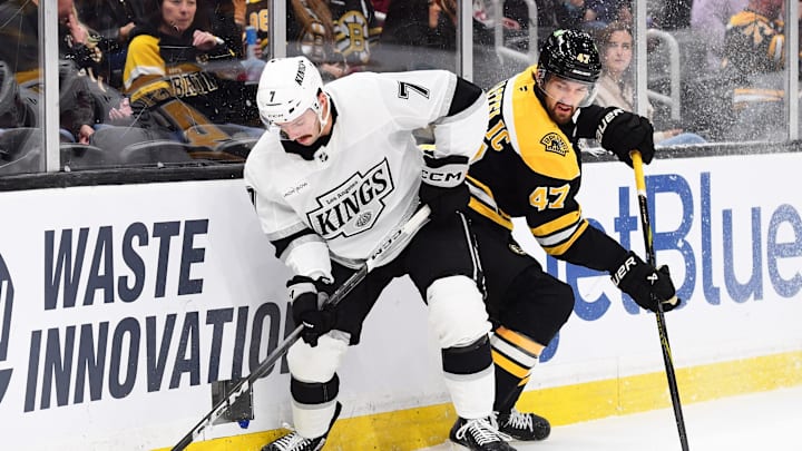 Oct 12, 2024; Boston, Massachusetts, USA;  Los Angeles Kings defenseman Kyle Burroughs (7) and Boston Bruins center Mark Kastelic (47) battle for the puck during the first period at TD Garden. Mandatory Credit: Bob DeChiara-Imagn Images