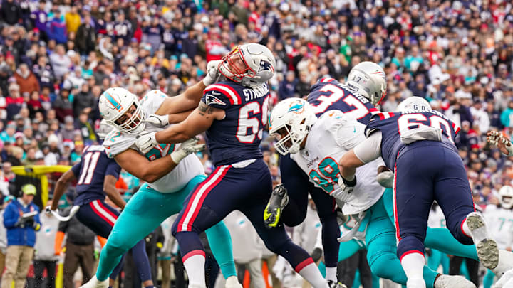 Jan 1, 2023; Foxborough, Massachusetts, USA; New England Patriots guard Cole Strange (69) hold off Miami Dolphins defense in the first half at Gillette Stadium. Mandatory Credit: David Butler II-Imagn Images