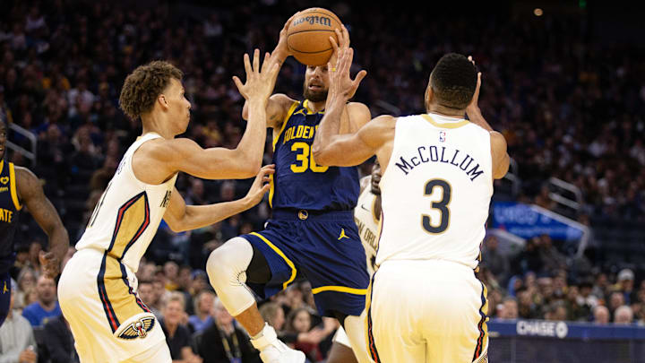 Golden State Warriors guard Stephen Curry (30) drives between New Orleans Pelicans guards Dyson Daniels (11) and CJ McCollum (3) during the third quarter at Chase Center. Mandatory Credit: D. Ross Cameron-Imagn Images