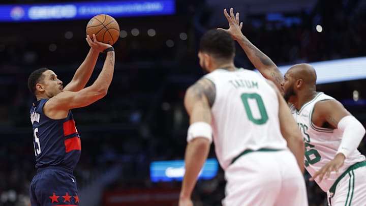 Nov 22, 2024; Washington, District of Columbia, USA; Washington Wizards guard Malcolm Brogdon (15) shoots the ball over Boston Celtics forward Xavier Tillman (26) as Boston Celtics forward Jayson Tatum (0) looks on in the second half at Capital One Arena. Mandatory Credit: Geoff Burke-Imagn Images