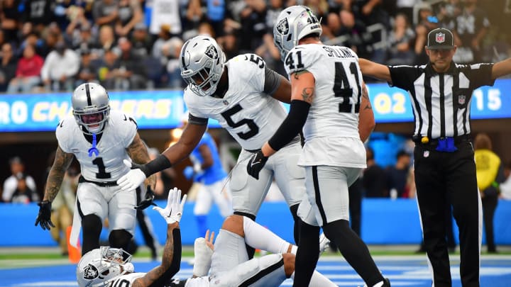 Oct 1, 2023; Inglewood, California, USA; Las Vegas Raiders safety Tre'von Moehrig (25) is helped up by linebacker Divine Deablo (5) after blocking a pass intended for Los Angeles Chargers tight end Donald Parham Jr. (89) during the first half at SoFi Stadium. Mandatory Credit: Gary A. Vasquez-USA TODAY Sports