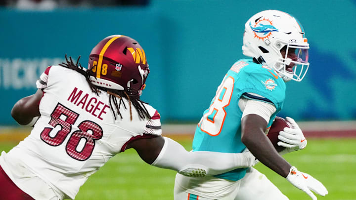 Miami Dolphins running back De'Von Achane (28) carries the ball defended by Washington Commanders linebacker Jordan Magee (58) in the second quarter during the 2025 NFL Madrid Game at Santiago Bernabeu Stadium.