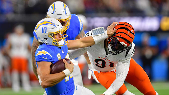 Nov 17, 2024; Inglewood, California, USA; Los Angeles Chargers quarterback Justin Herbert (10) is brought down by Cincinnati Bengals defensive end Trey Hendrickson (91) during the first half at SoFi Stadium. Mandatory Credit: Gary A. Vasquez-Imagn Images