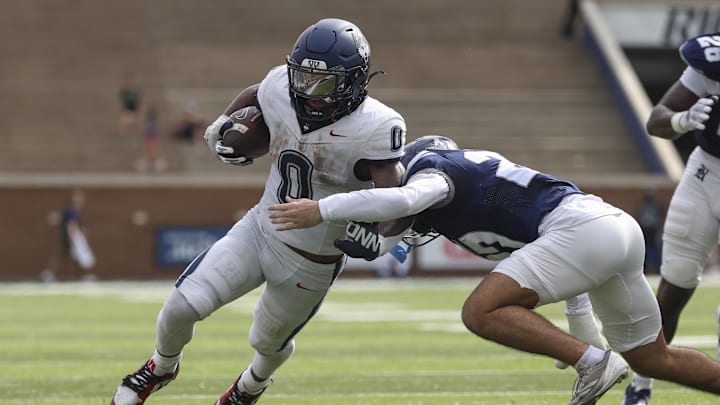 Oct 25, 2025; Houston, Texas, USA; UConn Huskies running back Cam Edwards (0) runs with the ball as Rice Owls safety Jack Kane (27) attempts to make a tackle during the second quarter at Rice Stadium. Mandatory Credit: Troy Taormina-Imagn Images