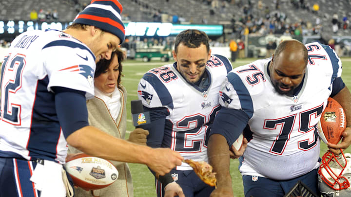 Nov 22, 2012; East Rutherford, NJ, USA; New England Patriots quarterback Tom Brady (12), safety Steve Gregory (28), and defensive tackle Vincent Wilfork (75) reach for a piece of a turkey while standing with NBC sports commentator Michele Tafoya after the game against the New York Jets on Thanksgiving at Metlife Stadium. The Patriots won the game 49-19. Mandatory Credit: Joe Camporeale-Imagn Images