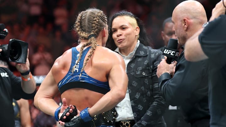 Jun 7, 2025; Newark, New Jersey, UNITED STATES; Kayla Harrison (blue gloves) talks to Amanda Nunes after defeating Julianna Pena (not pictured) in a bantamweight title bout during UFC 316 at Prudential Center. Mandatory Credit: Vincent Carchietta-Imagn Images