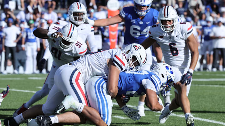 Oct 12, 2024; Provo, Utah, USA; Arizona Wildcats linebacker Lance Keneley (90) tackles Brigham Young Cougars running back LJ Martin (27) during the third quarter at LaVell Edwards Stadium. Mandatory Credit: Rob Gray-Imagn Images