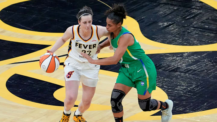 Caitlin Clark brings the ball up court as Brazil's Carina Dos Santos Martins defends her.