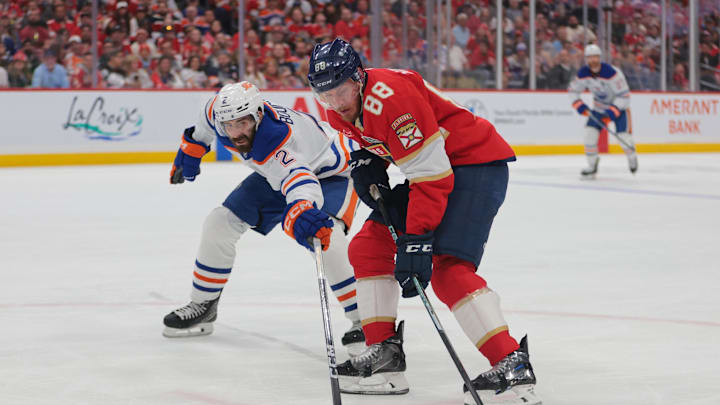 Jun 12, 2025; Sunrise, Florida, USA; Edmonton Oilers defenseman Evan Bouchard (2) reaches for the puck defending against Florida Panthers defenseman Nate Schmidt (88) during the second period in game four of the 2025 Stanley Cup Final at Amerant Bank Arena. 