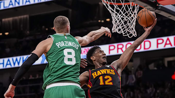 Mar 28, 2024; Atlanta, Georgia, USA; Atlanta Hawks forward De'Andre Hunter (12) goes to the basket against Boston Celtics center Kristaps Porzingis (8) during the second half at State Farm Arena. Mandatory Credit: Dale Zanine-Imagn Images