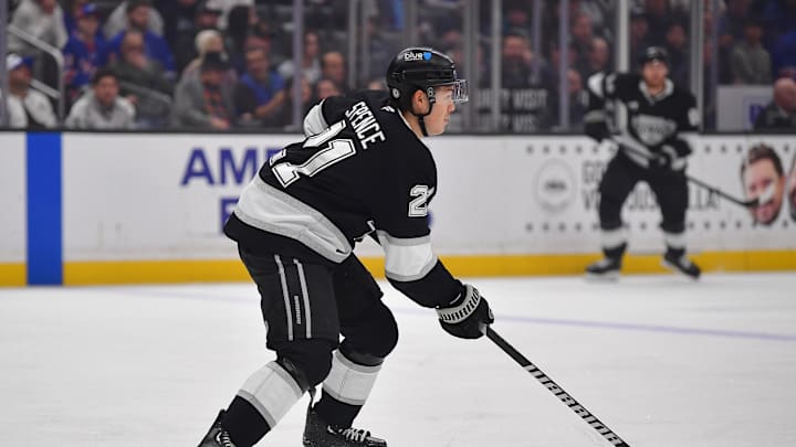 Mar 25, 2025; Los Angeles, California, USA; Los Angeles Kings defenseman Jordan Spence (21) controls the puck against the New York Rangers during the first period at Crypto.com Arena. Mandatory Credit: Gary A. Vasquez-Imagn Images