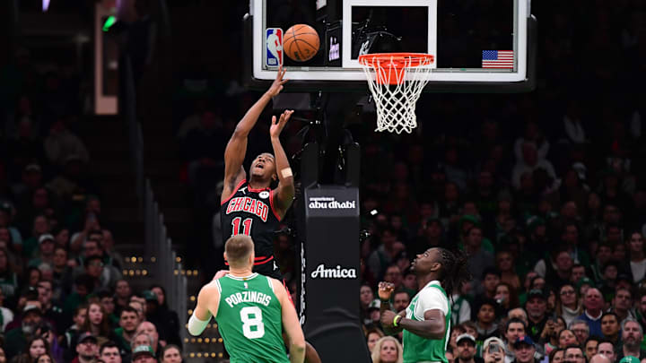 Jan 29, 2025; Boston, Massachusetts, USA; Chicago Bulls guard Ayo Dosunmu (11) shoots the ball while Boston Celtics center Kristaps Porzingis (8) and guard Jrue Holiday (4) look on during the first half at TD Garden. Mandatory Credit: Bob DeChiara-Imagn Images