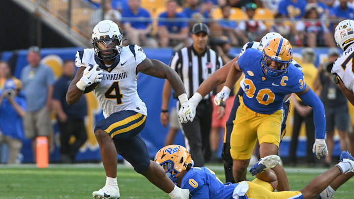 Sep 14, 2024; Pittsburgh, Pennsylvania, USA; West Virginia Mountaineers running back CJ Donaldson Jr. (4) breaks a tackle attempt by Pittsburgh Panthers linebacker Braylon Lovelace (on ground) in the second quarter at Acrisure Stadium. Mandatory Credit: Barry Reeger-Image Images